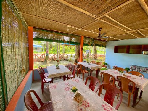 ein Esszimmer mit Tischen und Stühlen und Fenstern in der Unterkunft Garden View Restaurant and Home Stay in Neill Island