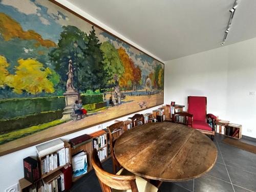 Cette chambre comprend une table et des chaises en bois ainsi qu'une grande peinture. dans l'établissement Maison de vacances à Sossais - Campagne calme, 3 chambres, proche sites touristiques - FR-1-541-172, à Sossais