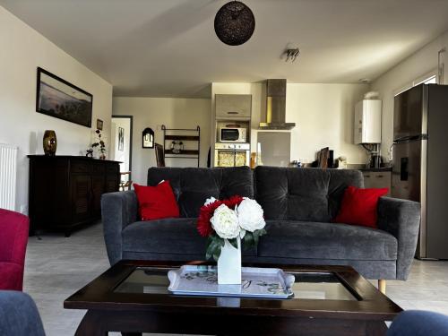 un salon avec un canapé et une table avec des fleurs dans l'établissement Maison PMR plain-pied avec jardin, 3 chambres, 6 pers., animaux sur demande, proche Ria d'Etel - FR-1-397-85, à Belz