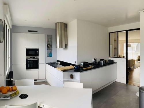 - une cuisine avec des armoires blanches et un bol d'oranges sur une table dans l'établissement Charmant Duplex 6-7 Pers avec Wifi et Parking à La Baule - FR-1-392-244, à La Baule-les-Pins