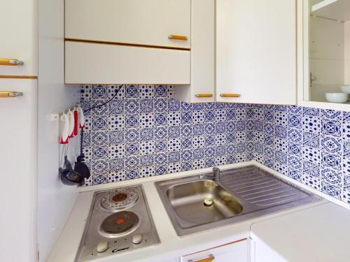 - une cuisine avec un évier et du carrelage bleu et blanc dans l'établissement Joli studio à Menton avec terrasse et garage - FR-1-196-376, à Menton