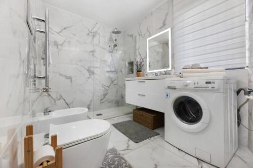 a white bathroom with a washing machine in it at Dina’s Flower House in Lierna
