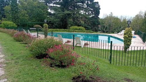 a fence in front of a swimming pool with flowers at Posada los Cedros in La Cumbre