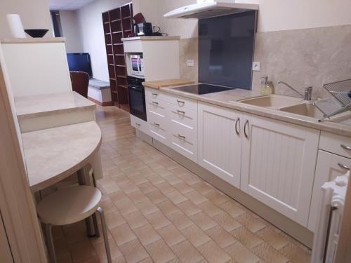 une cuisine avec des armoires blanches, un évier et une cuisinière dans l'établissement Grand T2 Hypercentre, rue calme, à Ax-les-Thermes