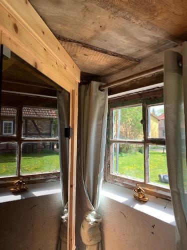 a room with two windows in a house at Historisches Bauernhaus für 8 Personen mit Luxus und Natur auf 2 Etagen ideal für Familien und Hunde 2500m2 eingezäunt an der Ostsee in Niepars