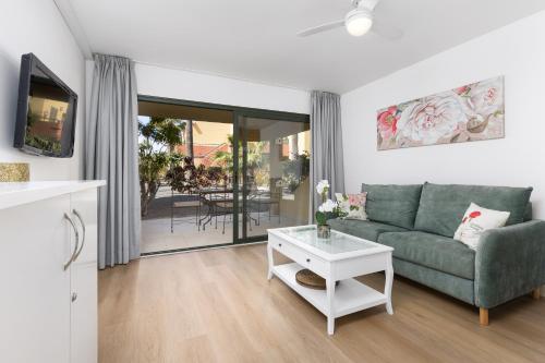 ein Wohnzimmer mit einer grünen Couch und einem Tisch in der Unterkunft Home2Book Zen Oasis Apt Pool & Terrace, Corralejo in Corralejo