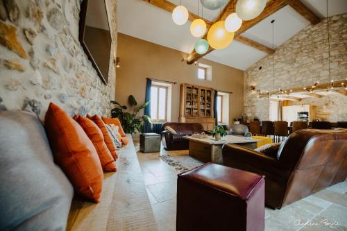 a living room with leather furniture and a stone wall at Domaine de coulette in Vallon-Pont-dʼArc