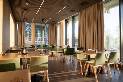 a restaurant with tables and chairs and large windows at Amenity Hotel & Resort Česká Kanada in Nová Bystřice