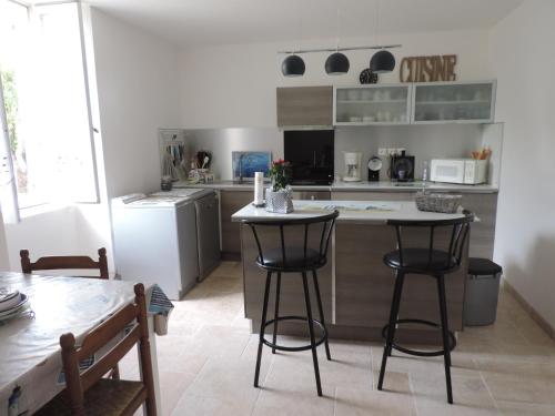 une cuisine avec un comptoir et deux tabourets de bar dans l'établissement Gite Terre Océane, à Plassay