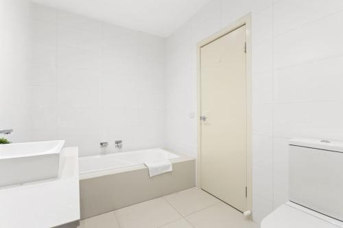 a white bathroom with a tub and a sink at Domi Rentals The Chadstone Homes in Chadstone