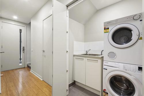 a white laundry room with a washer and dryer at The Brighton Townhouse in Melbourne