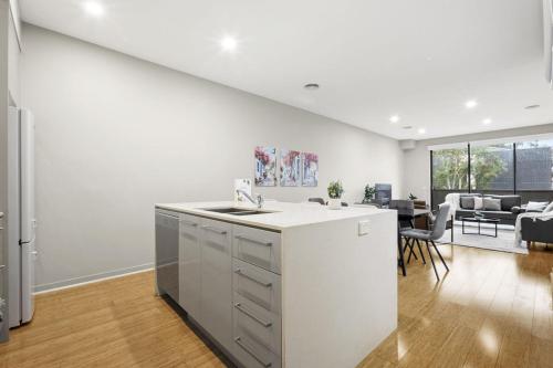 a white kitchen with a sink and a living room at The Brighton Townhouse in Melbourne