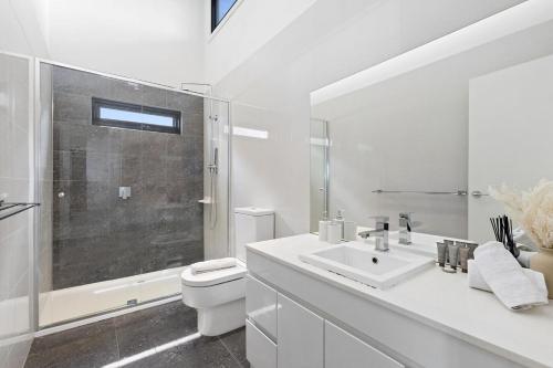 a white bathroom with a toilet and a sink at The Chadstone Home in Chadstone
