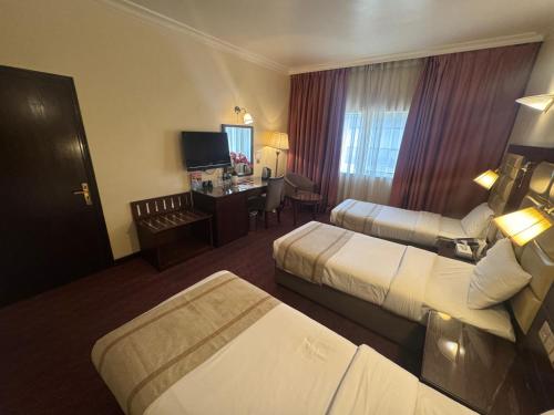 a hotel room with two beds and a desk at Orchid Hotel Deira in Dubai