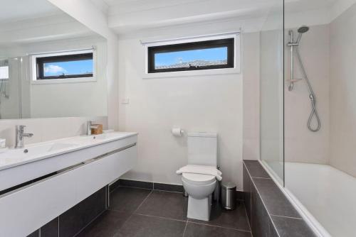 a bathroom with a toilet and a sink and a shower at Domi Rentals - The Mill Residence in Clayton North