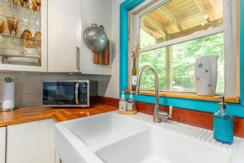 a kitchen with a sink and a microwave and a window at Secluded Cabin with Quality Furnishing and Hot Tub in Leicester