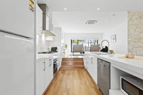 a kitchen with white counter tops and wooden floors at Domi Rentals The Chadstone Homes in Chadstone