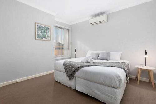 una camera da letto bianca con un letto e una finestra di Domi Rentals - The Lona Townhouse a Clayton North