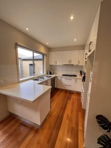 a large kitchen with white cabinets and a large window at The Blackburn Residences in Notting Hill