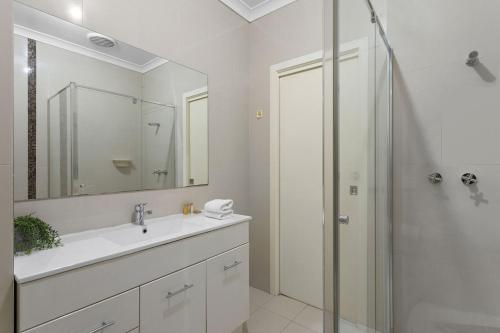 クレイトン・ノースにあるThe Lantana Residenceの洗面台とシャワー付きの白いバスルーム