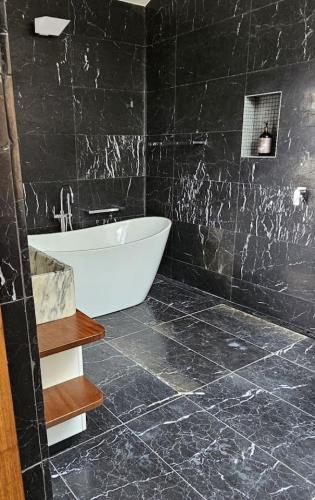 a bathroom with a bath tub and a black wall at Pagoda Point in Bar Point