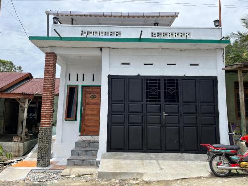 a house with a black door and a motorcycle in front at SEE BUKIT LAWANG Homestay & Tours in Bukit Lawang