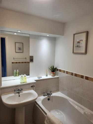 a bathroom with a sink and a tub and a mirror at River Ayr View-Coorie Doon Stays in Ayr