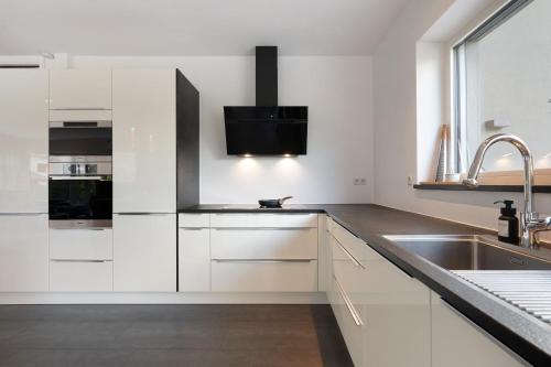 a kitchen with white cabinets and a sink at New Opening Vinea Guesthouse in Cornedo all'Isarco