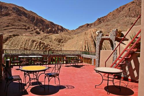 a patio with tables and chairs and a mountain at Maison d'Hôte Valentine in Tinerhir
