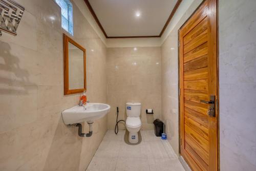 a bathroom with a white toilet and a sink at Lungguh Penida Hut in Nusa Penida