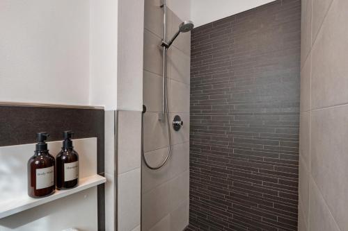 a bathroom with a shower with bottles of wine on a shelf at New Opening Vinea Guesthouse in Cornedo all'Isarco