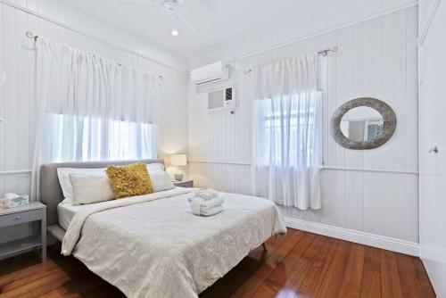 a white bedroom with a bed and a mirror at Family Friendly, Pool, 9km to City by Custom Bnb Hosting in Brisbane
