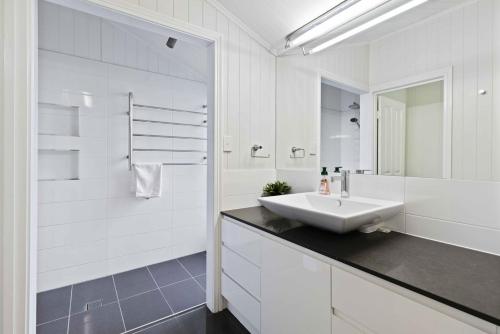 a white bathroom with a sink and a mirror at Family Friendly, Pool, 9km to City by Custom Bnb Hosting in Brisbane