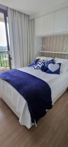 a bedroom with a large bed with blue and white pillows at Flat Condomínio Vista Azul - Pedra Azul in Pedra Azul
