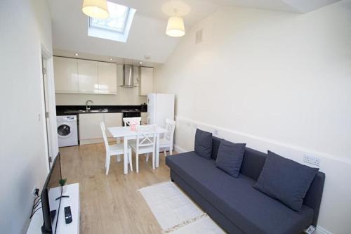 a living room with a blue couch and a kitchen at Lovely 1-Bedroom Flat in London near Blackhorse Rd in London