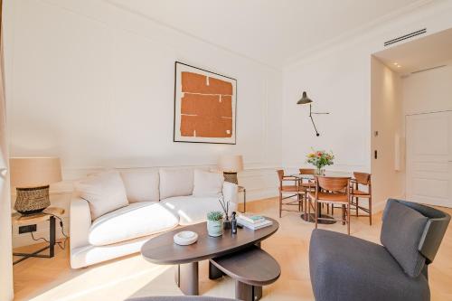 un salon avec un canapé blanc et une table dans l'établissement La Guitare 22 - Spacious 1 BR apartment in the center of Cannes, right behind Grand Hotel, à Cannes