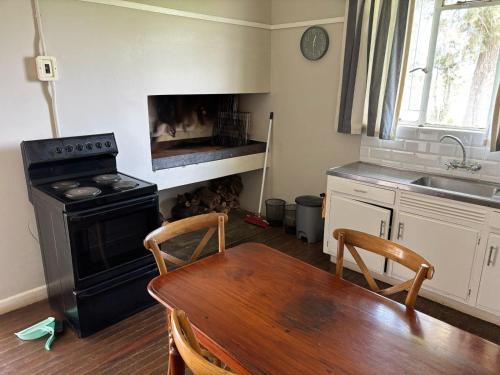 a kitchen with a table and a stove and a sink at Pretoriuskuil in Aberdeen
