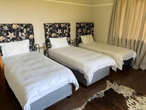 a room with two beds with white sheets and a rug at Pretoriuskuil in Aberdeen