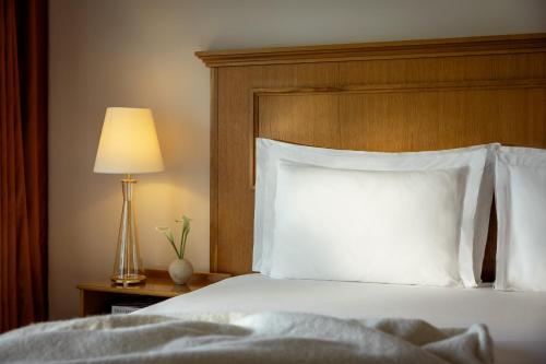 a bedroom with a bed with white pillows and a lamp at Corinthia Palace Malta in Attard