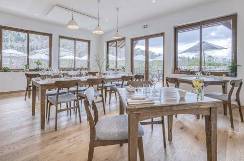a dining room with tables and chairs and windows at Auberge du pont de l'Abîme in Gruffy