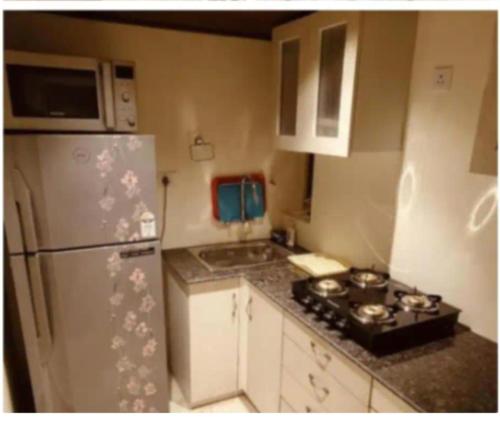 a kitchen with a white refrigerator and a stove at ELDORA - LUXURY of LEISURE in Bhīm Tāl