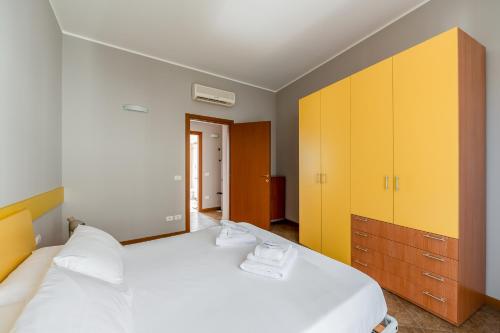 a bedroom with a large white bed with yellow cabinets at Residence Due Spade - Free Parking in Melzo