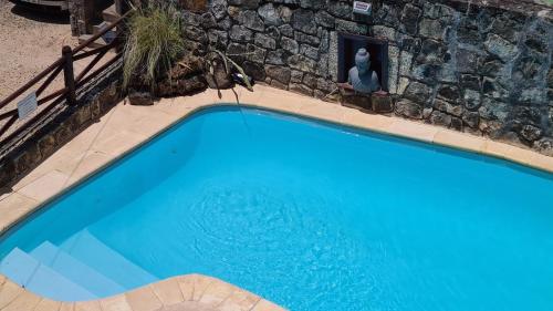 a blue swimming pool with a statue next to a stone wall at Le Morne View Duplex in Rivière Noire
