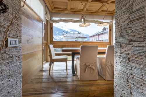 a dining room with a table and chairs and a window at Sottovento Luxury Hospitality in Bormio