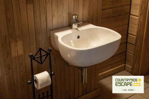 a bathroom with a white sink in a wooden wall at Countryside Escape - Lake Rooms in Trakai