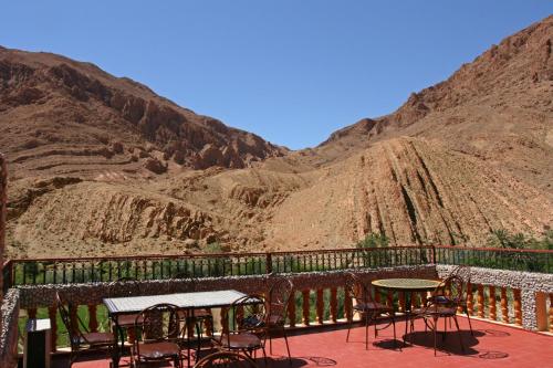 a patio with tables and chairs and a mountain at Maison d'Hôte Valentine in Tinerhir