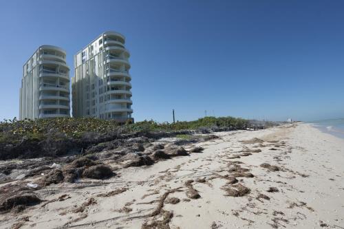 a sandy beach with two tall buildings in the background at Temporada B52 in Telchac Puerto