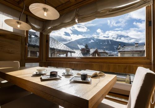 a table with a view of a mountain through a window at Sottovento Luxury Hospitality in Bormio