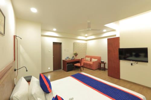 a bedroom with a bed and a desk and a television at Zip By Spree Hotels Kolhapur in Kolhapur