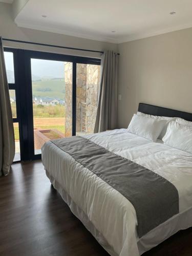 a bedroom with a large bed and a large window at The Gorge View at Highland Gate in Dullstroom